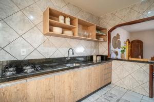 eine Küche mit Holzschränken und einer Spüle in der Unterkunft Casa térrea com 03 quartos em Canto Grande in Canto Grande + 31 Fotos