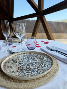 a table with a plate and wine glasses on it at El Molí Glamping Escapada Romántica in Adzaneta