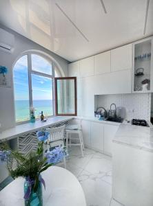 eine weiße Küche mit einem Tisch und einem Fenster in der Unterkunft Вид на море, ЖК Avinion in Odessa