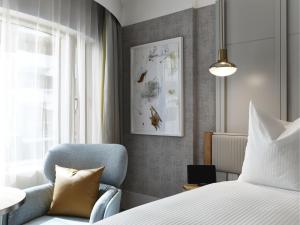a bedroom with a bed and a blue chair at The Porter House Hotel Sydney - MGallery in Sydney