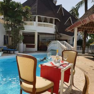 a table with wine glasses on it next to a pool at Cozy Beachside Retreat in Diani Kwale County in Galu