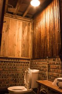 a bathroom with a toilet and a wooden wall at Mèo Vạc Giấc Xưa Homestay in Mèo Vạc