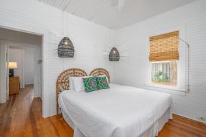 a white bedroom with a bed and a window at Shirley Road Cottage by Tybee Cottages in Tybee Island