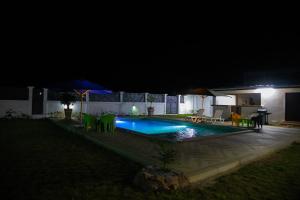 AssinieRésidence AL的夜间游泳池,配有椅子和遮阳伞