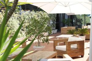 ジュリアーノ・イン・カンパーニアにあるHotel Barbarella Swimmingのテーブルと椅子と傘のあるパティオ