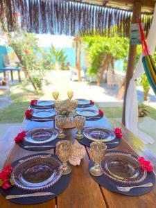 a wooden table with blue plates and wine glasses at Bangalôs Flecheiras de Canaã in Flecheiras