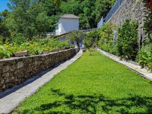 a garden with green grass next to a stone wall at Casa dei Cigni in Cannobio +52 photos