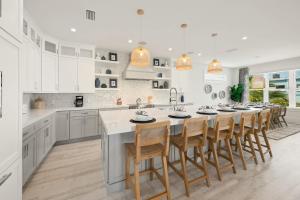 a kitchen with white cabinets and a large island with bar stools at Beach View Paradise - New Anna Maria Island Home in Ilexhurst