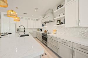 a white kitchen with white cabinets and a sink at Beach View Paradise - New Anna Maria Island Home in Ilexhurst