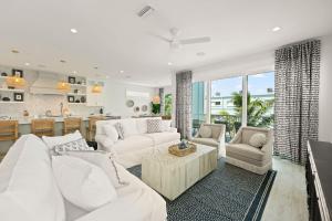 a living room with white furniture and a kitchen at Beach View Paradise - New Anna Maria Island Home in Ilexhurst