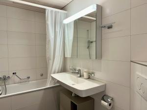 a white bathroom with a sink and a mirror at City Cosy - 2 Bedroom & Free Parking - Bern in Bern