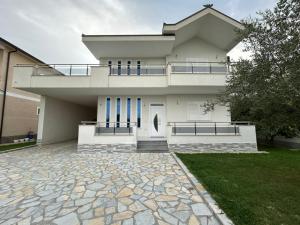 a white house with a balcony and a driveway at Miri House in Domje