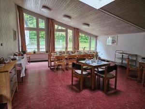 a dining room with tables and chairs and windows at Zimmer 8 in Gomadingen