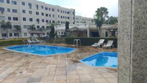 two swimming pools in a courtyard with a building at Apartamento 2 quartos Serra in Serra