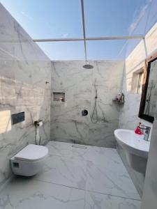 une salle de bain blanche avec toilettes et lavabo dans l'établissement City Retreat Arusha, à Arusha