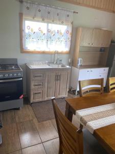 a kitchen with a sink and a stove and a table at Cabaña Paihuen in Puerto Octay +2 photos