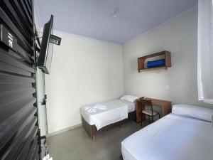 a small room with two beds and a desk at Vithor Hotel in Cassilândia