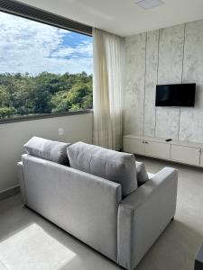a living room with a couch and a large window at Promoção em Bombinhas até 4 pessoas c Piscina Aquecida in Bombinhas