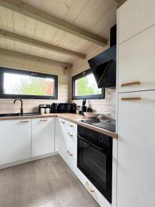 eine Küche mit weißen Schränken und einem schwarzen Herd in der Unterkunft Tiny House Ještěd in Liberec
