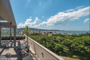 a balcony with tables and chairs and a view of the ocean at Promoção em Bombinhas até 4 pessoas c Piscina Aquecida in Bombinhas