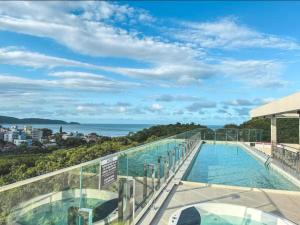 a swimming pool on a building with a view of the ocean at Promoção em Bombinhas até 4 pessoas c Piscina Aquecida in Bombinhas