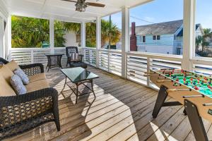 a screened porch with a couch and a table with a game at SeaStarr by Tybee Cottages in Tybee Island