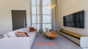 a living room with a white couch and a flat screen tv at Casa em Marechal Deodoro com jacuzzi in Marechal Deodoro
