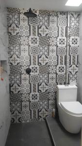 a bathroom with a toilet and a black and white tile wall at Departamento para PERUMIN AREQUIPA in La Apacheta