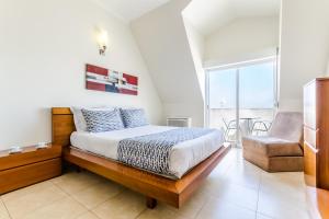 a bedroom with a bed and a chair at Apartamentos do Mar Peniche in Peniche