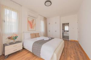 a white bedroom with a bed and a window at TelMar Royal Villa Sea View in Mazotos
