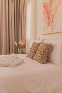 a white bed with a pillow and a vase of flowers at TelMar Royal Villa in Mazotos