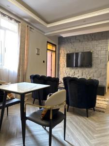 a waiting room with a table and chairs and a tv at Chic and Cozy studio Kyanja in Kampala +6 photos