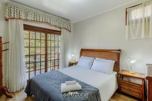 ein Schlafzimmer mit einem Bett und einem großen Fenster in der Unterkunft Apto 300m do lago negro em Gramado/RS RLN0104 in Gramado