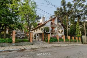 ein Haus an der Seite einer Straße mit einem Zaun in der Unterkunft Apto 300m do lago negro em Gramado/RS RLN0104 in Gramado