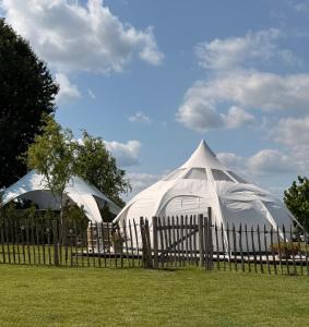 ein großes weißes Zelt hinter einem Holzzaun in der Unterkunft Glamping & wellness Moonlight in Brakel