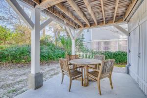 a table and chairs on a porch with a pergola at Gone Coastal by Tybee Cottages in Tybee Island
