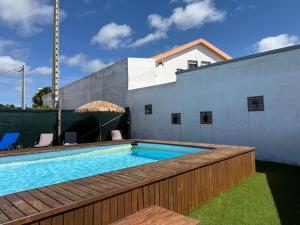 a swimming pool with a wooden deck next to a building at Refúgio Dourado in Lourinhã