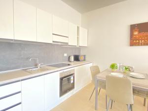 a kitchen with white cabinets and a table with chairs at Suite Emilia 7 in Bologna