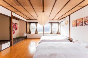 two beds in a room with two windows at SkySTAGE十人町 in Nagasaki