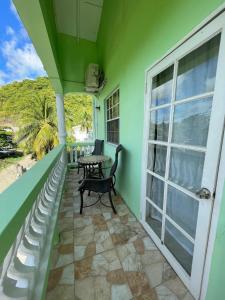 a green house with a balcony with a table and a window at Hibiscus Apartment in Corinthe