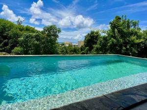 a swimming pool with blue water and trees at Villa TULIA in Sainte-Luce