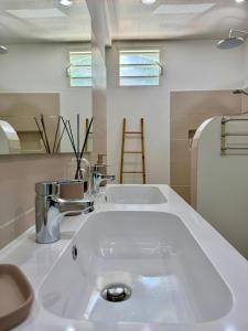 a white bathroom with a sink and a mirror at Villa TULIA in Sainte-Luce