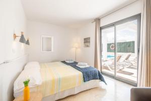a white bedroom with a bed and a balcony at Villa Sam 3 in Can Picafort +16 photos