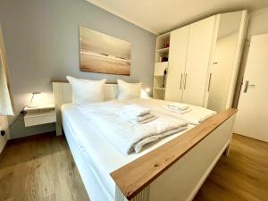 une chambre avec un grand lit blanc avec des serviettes dessus dans l'établissement Haus Ostseewelle Wohnung Nr. 2, à Kühlungsborn