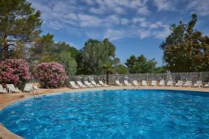 a large swimming pool with chairs and flowers at Mobil-home in La Roque-dʼAnthéron