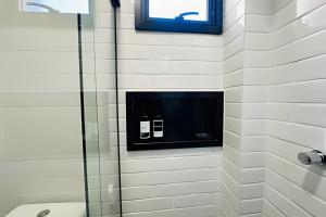 a bathroom with a shower with a tv on the wall at Loft 108 - Conforto e praticidade no Santa Mônica. in Uberlândia +15 photos