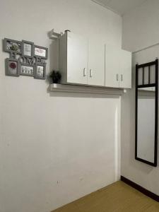 a kitchen with white cabinets and a shelf on the wall at Merdeka 19A in Taiping
