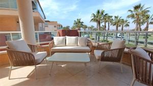 einen Balkon mit einem Sofa, Stühlen und Palmen in der Unterkunft Casita Luxury- Grecia 3- Precioso apartamento en Hacienda del Alamo in Los Guerreros