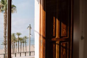 a door looking out at a beach with palm trees at Esquerdo 22 by Seaward Suites in Villajoyosa +12 photos