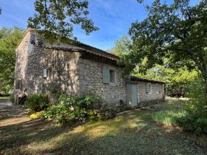 - un vieux bâtiment en pierre dans une cour arborée dans l'établissement La Bastide des Chênes Lacoste, à Lacoste